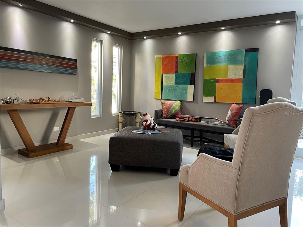 A modern living room features a gray sofa, a large ottoman, and two abstract paintings — 7 ALTURAS DE TORRIMAR UNIT 11-7, GUAYNABO, PR