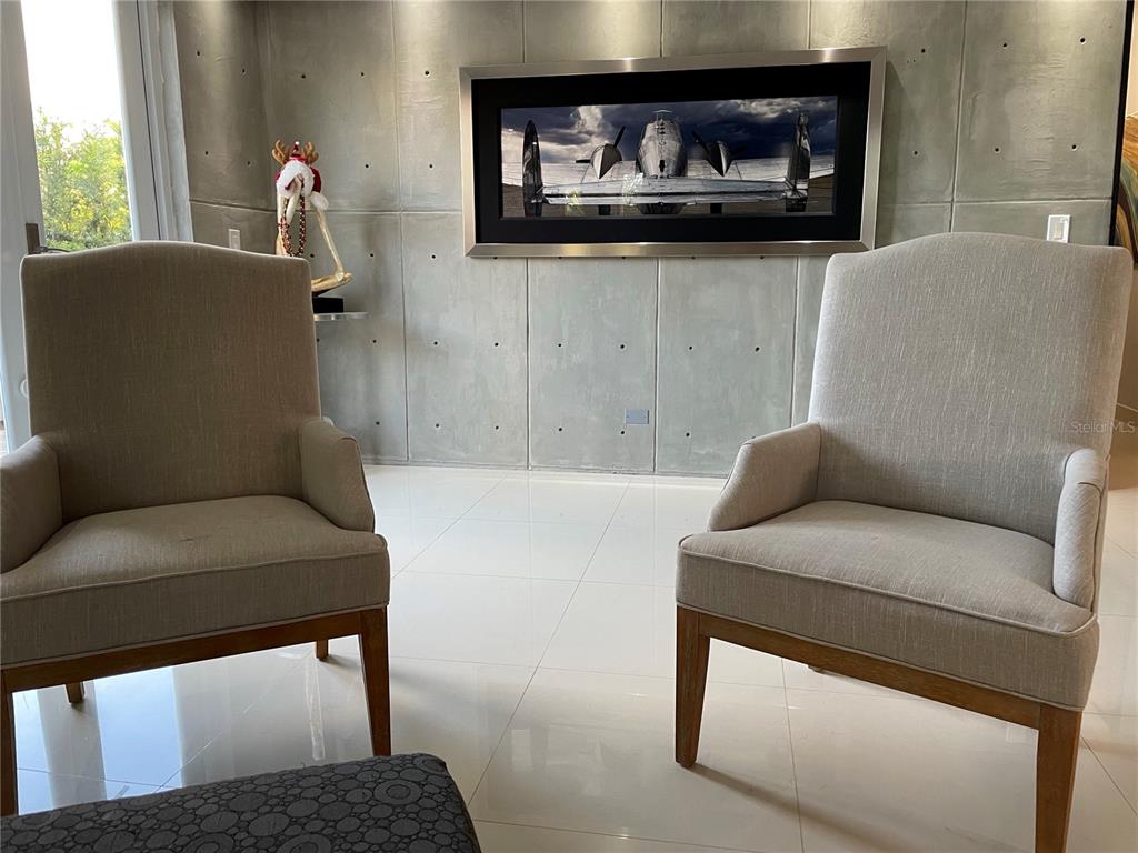 Two armchairs face a wall with concrete panels and a framed airplane photograph — 7 ALTURAS DE TORRIMAR UNIT 11-7, GUAYNABO, PR