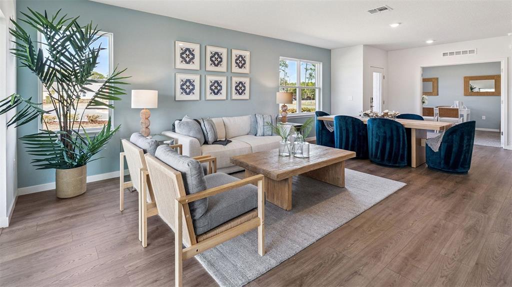 A living room features light blue walls, wood flooring, a sofa, armchairs, and a dining area — 2512 KINSALE LANE, ORMOND BEACH, FL