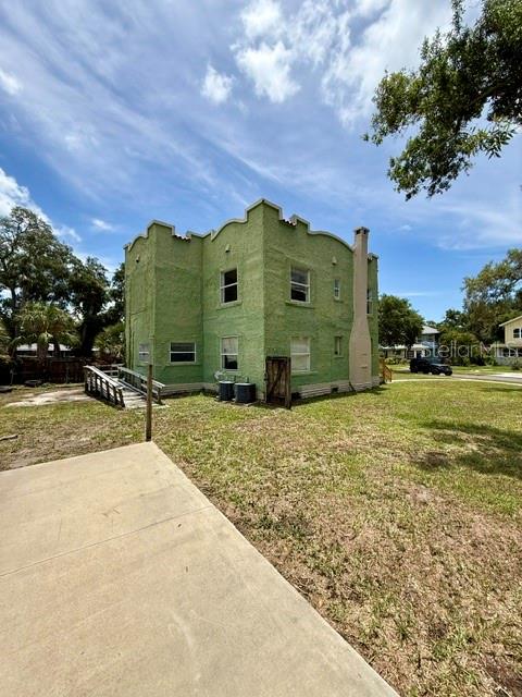 A two-story green stucco building with a crenelated roofline stands on a grassy lot — 2314 TRELAIN DRIVE S, ST PETERSBURG, FL