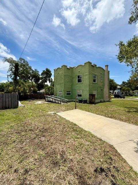 A green two-story building with a ramp stands on a grassy lot under a blue sky — 2314 TRELAIN DRIVE S, ST PETERSBURG, FL