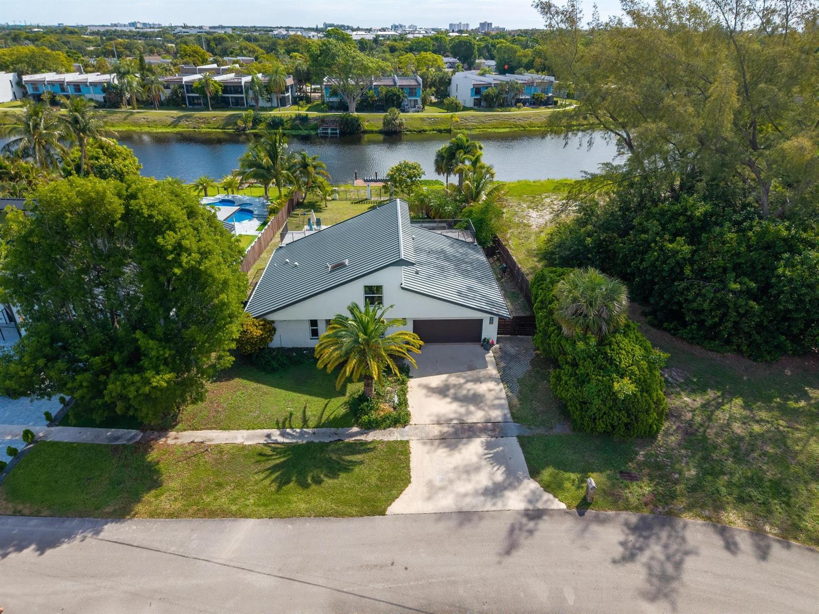 An aerial view of a single-story house with a metal roof, driveway, and backyard pool — 33 Oregon Lane, Boca Raton FL 33487, BOCA RATON, FL