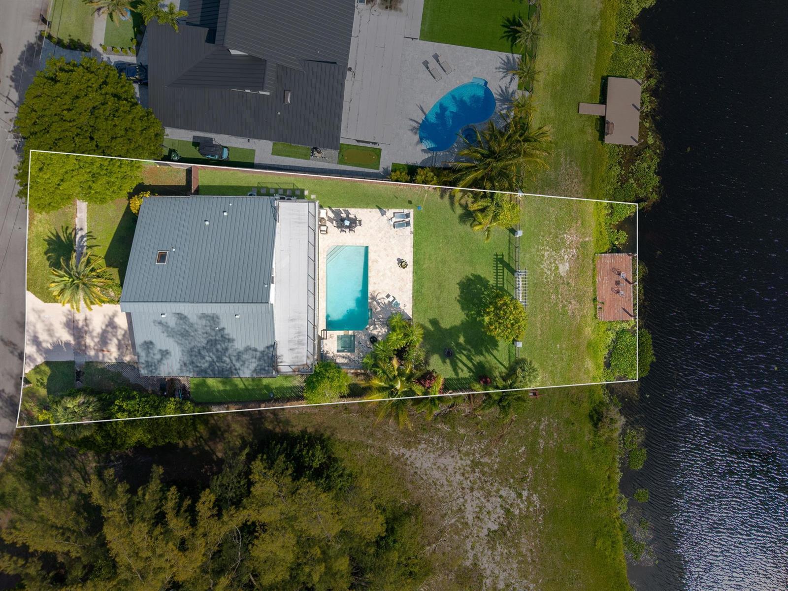 An aerial view shows a house with a pool, patio, and dock on a lake — 33 Oregon Lane, Boca Raton FL 33487, BOCA RATON, FL