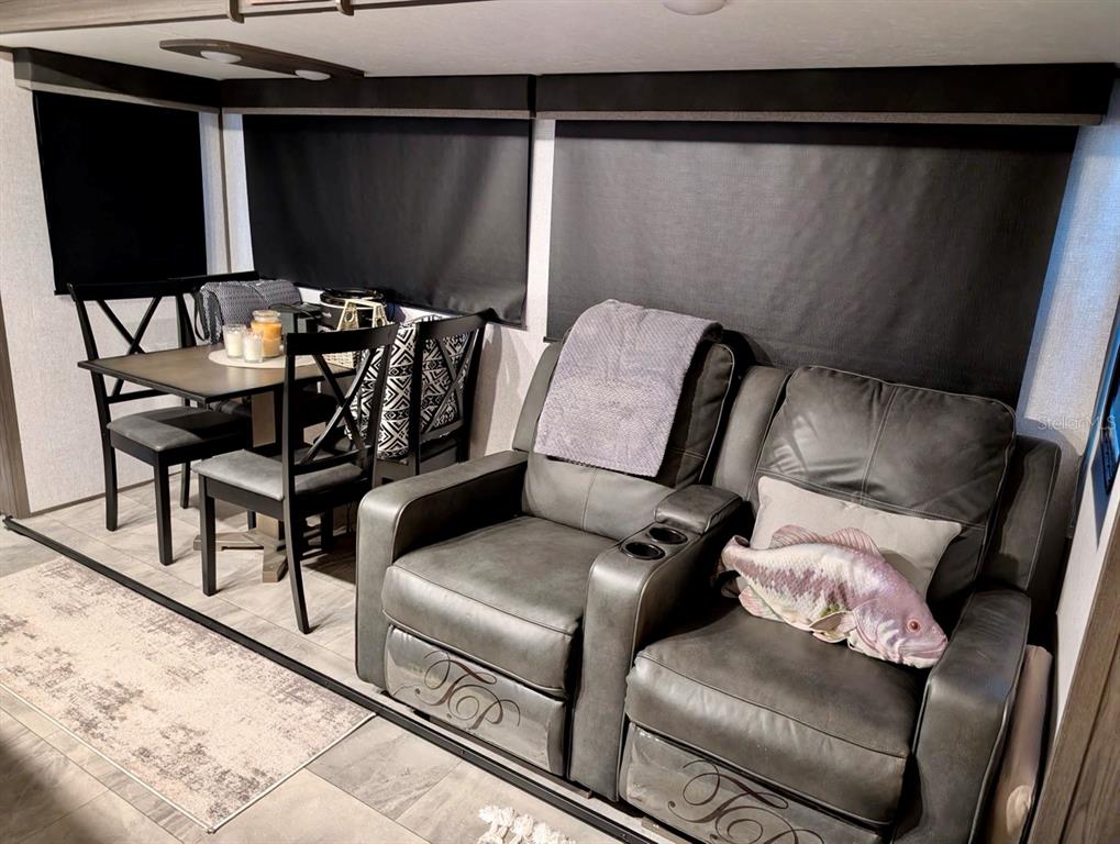 A dining area with a table and chairs next to a gray leather reclining sofa — 25338 NE 141ST STREET, SALT SPRINGS, FL