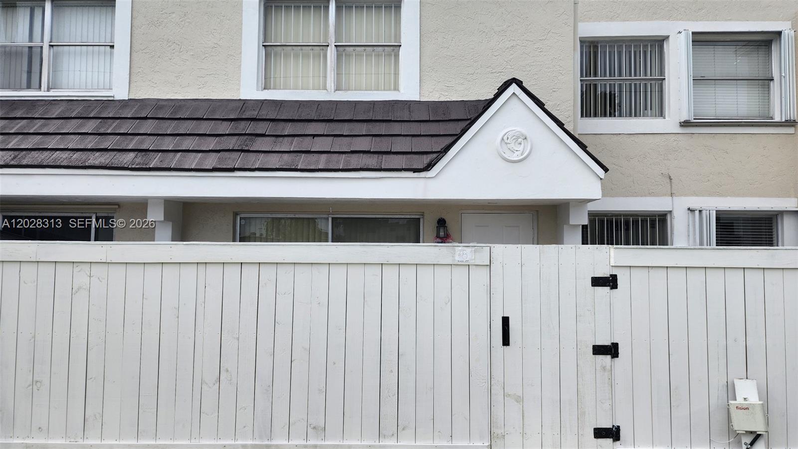 A white wooden fence stands in front of a two-story townhouse with a dark roof — 4540 SW 68th Ct Cir # 7, Miami FL 33155, MIAMI, FL