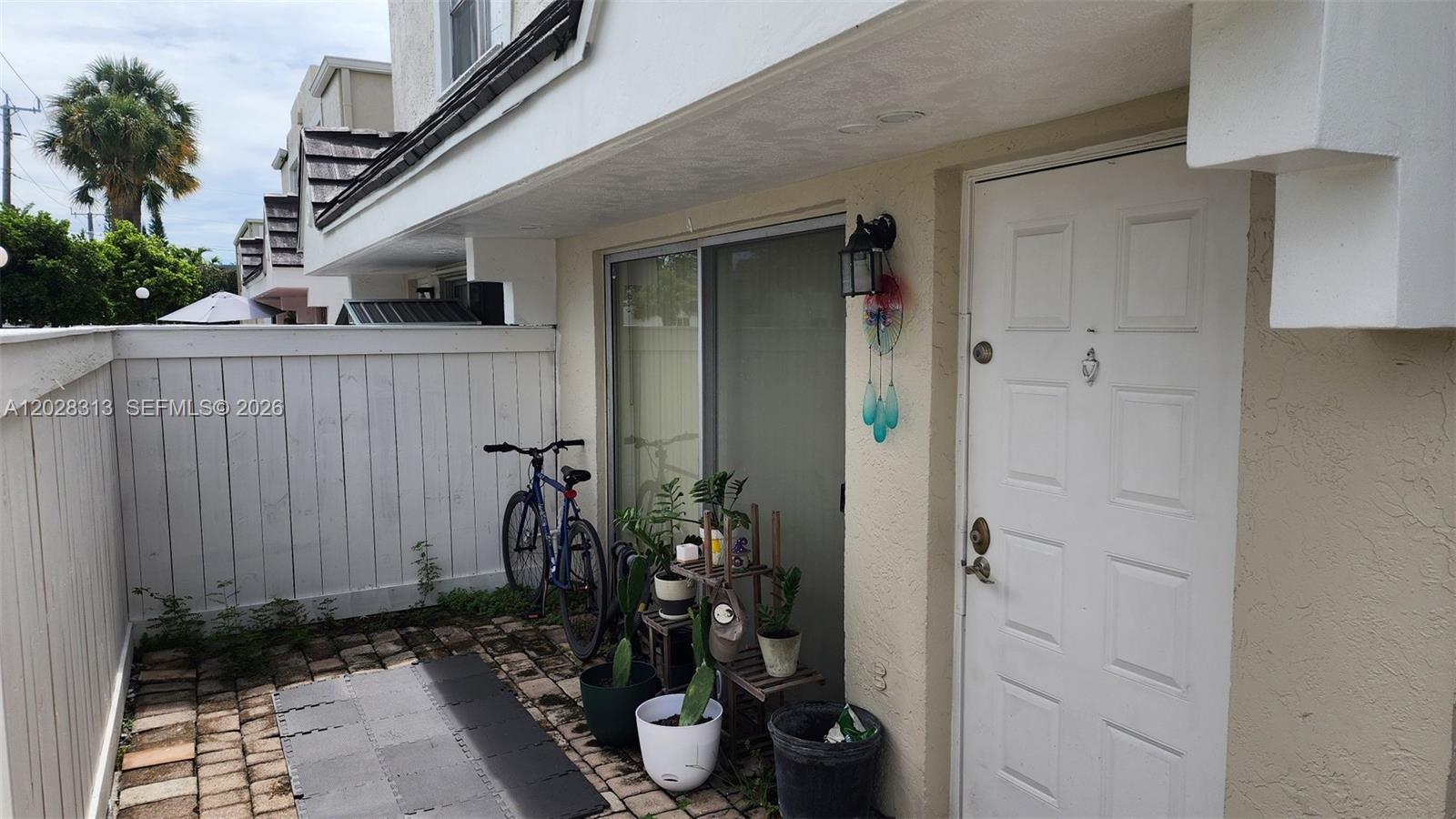 A paved patio area features a bicycle, potted plants, and a white front door — 4540 SW 68th Ct Cir # 7, Miami FL 33155, MIAMI, FL