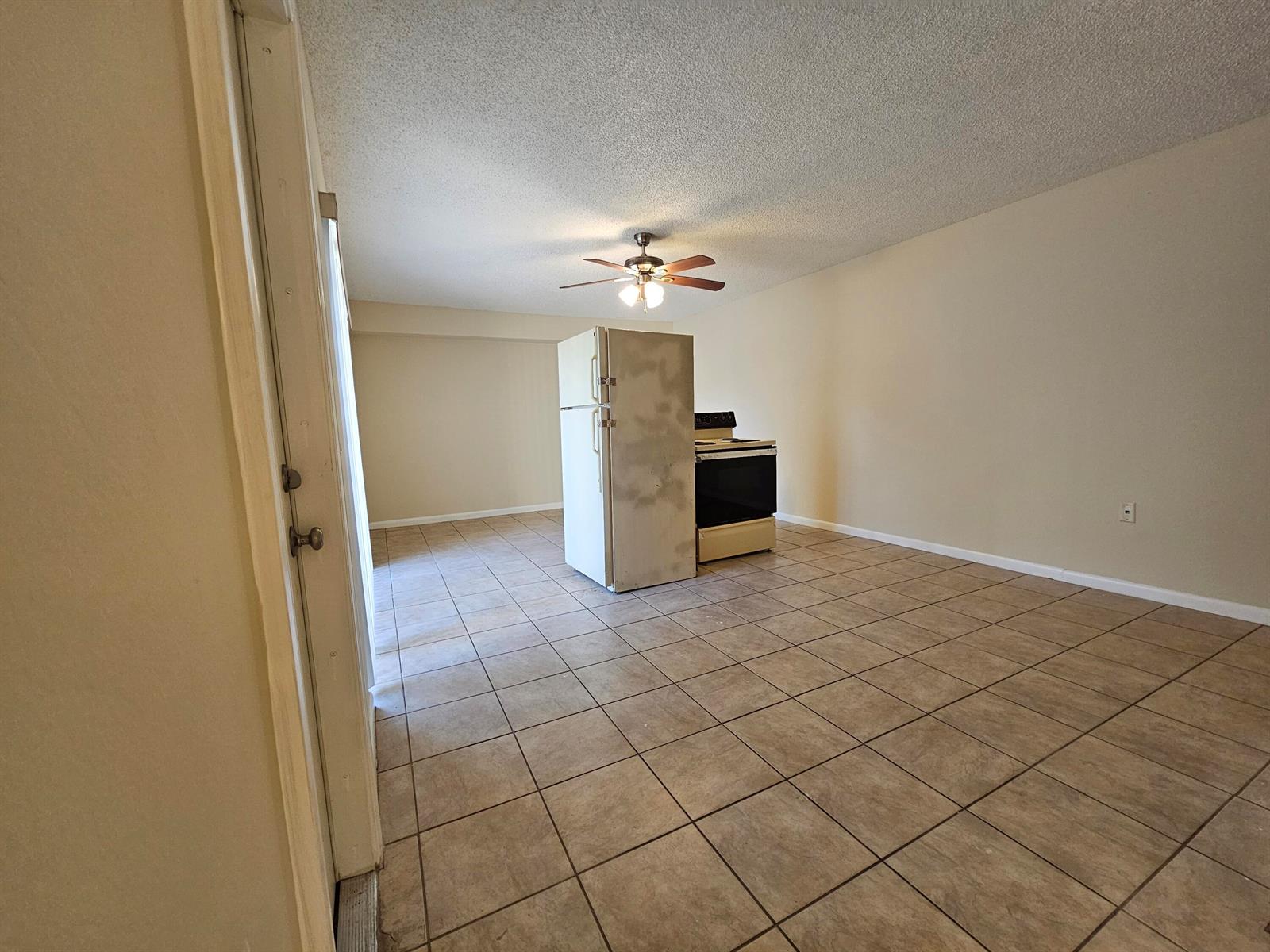 An open-concept kitchen area features tile flooring, a ceiling fan, and a freestanding refrigerator and stove — 5152 51st Way, West Palm Beach FL 33409, WEST PALM BEACH, FL