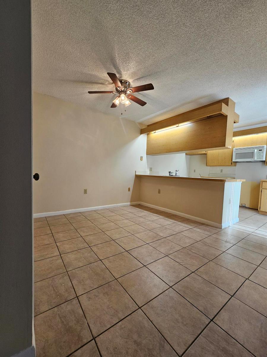 A dining area with tile flooring and a ceiling fan opens to a kitchen counter — 5152 51st Way, West Palm Beach FL 33409, WEST PALM BEACH, FL