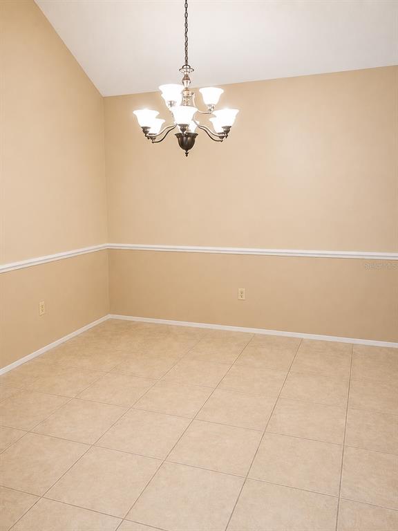A dining room with beige walls, chair rail molding, a chandelier, and light-colored tile flooring — 546 CIDERMILL PL, LAKE MARY, FL