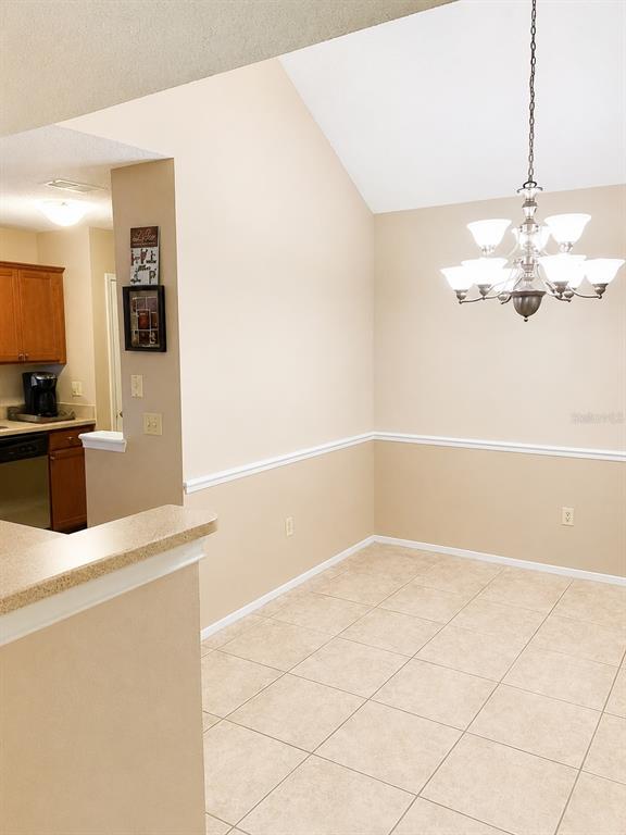 A dining area with tile floors, a chandelier, and a chair rail, adjacent to a kitchen — 546 CIDERMILL PL, LAKE MARY, FL