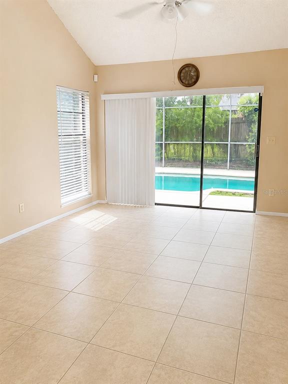 A room with beige tile flooring, a vaulted ceiling, a sliding glass door, and a pool — 546 CIDERMILL PL, LAKE MARY, FL