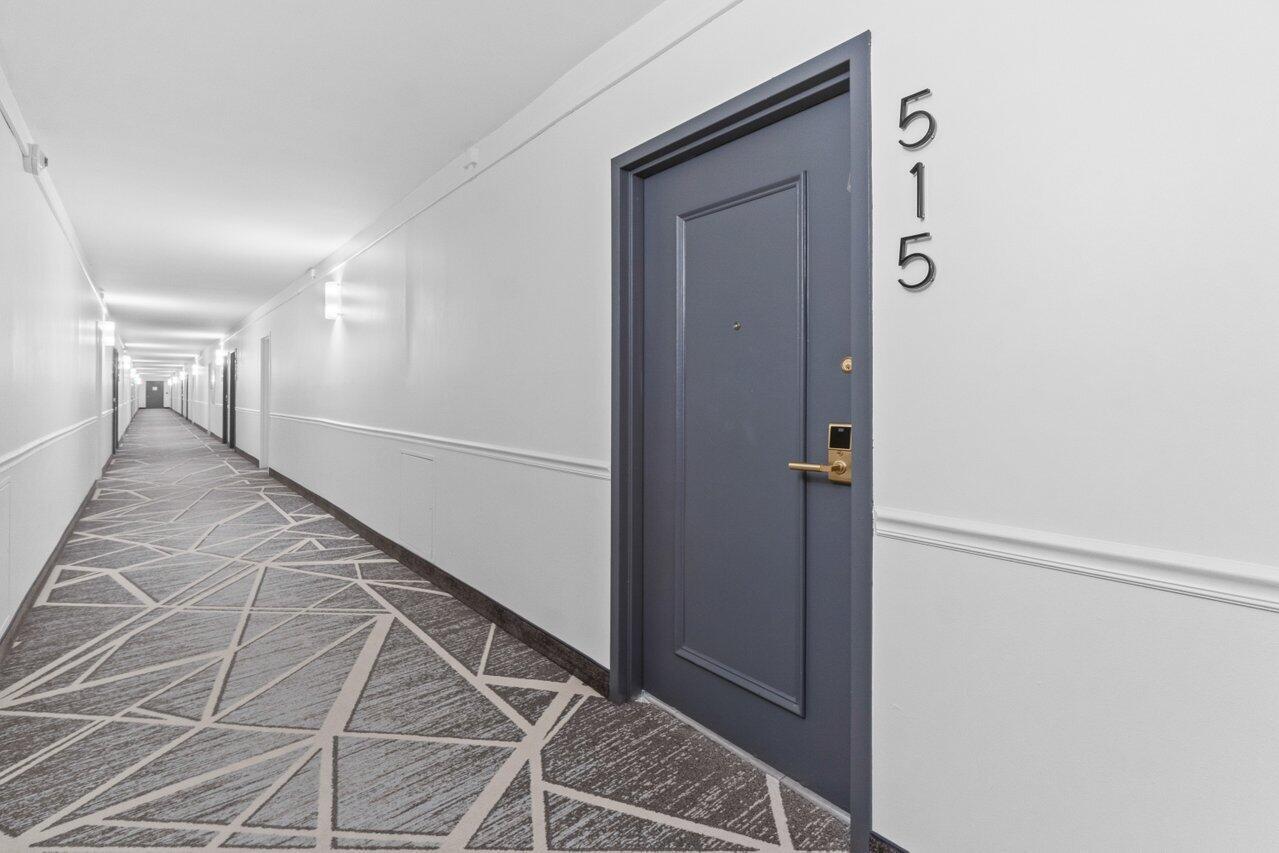 A long hotel hallway features gray doors, white walls, and a geometric patterned carpet — 3450 S Ocean Boulevard # 5150, Palm Beach FL 33480, PALM BEACH, FL