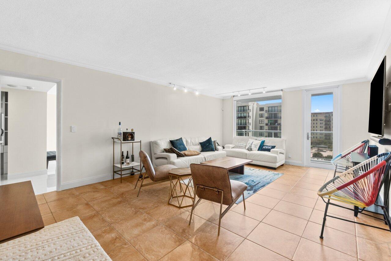 A living room with tile flooring, a white sofa, two accent chairs, and a balcony door — 3450 S Ocean Boulevard # 5150, Palm Beach FL 33480, PALM BEACH, FL