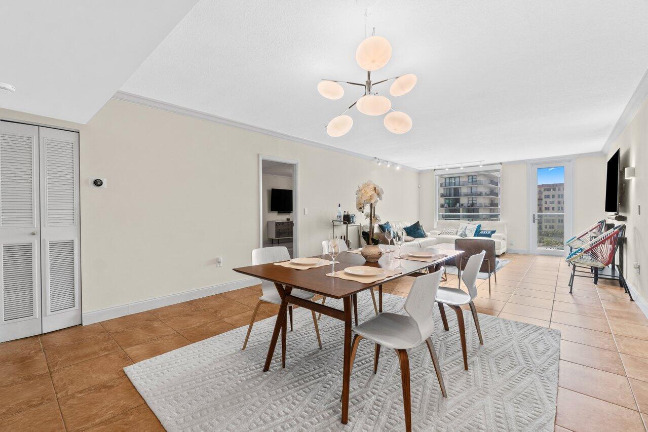 A dining area with a wooden table and modern chandelier opens into a living room — 3450 S Ocean Boulevard # 5150, Palm Beach FL 33480, PALM BEACH, FL