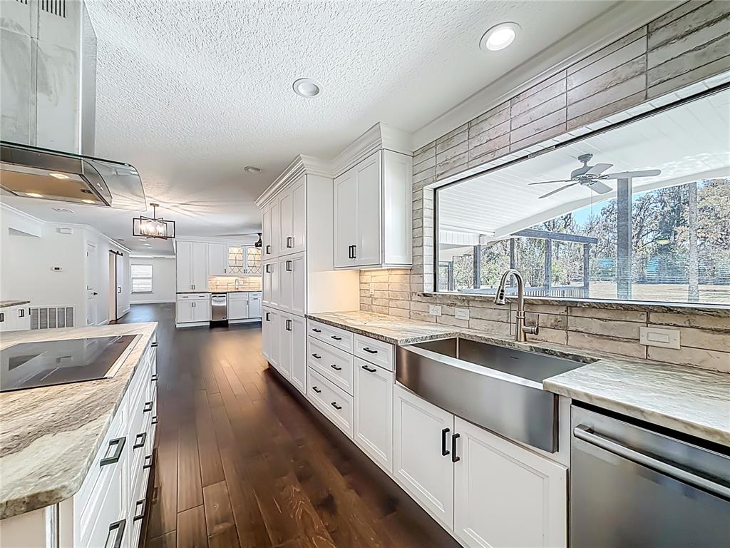 A modern kitchen features white cabinetry, stainless steel appliances, a farmhouse sink, and wood flooring — 3575 SW 24TH AVENUE ROAD, OCALA, FL
