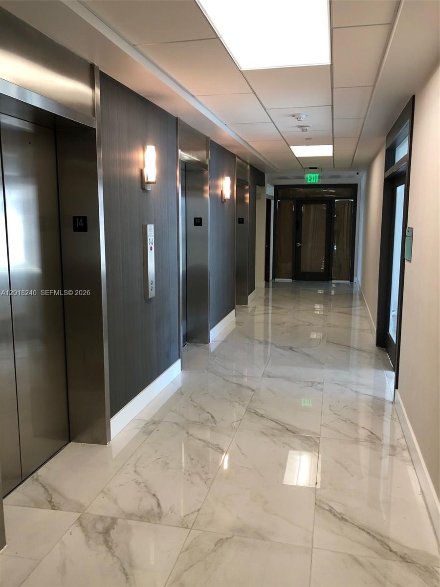 A hallway features marble-look tile flooring, elevator doors, and wall-mounted sconces — 150 SE 2nd Ave # 1402, Miami FL 33131, MIAMI, FL