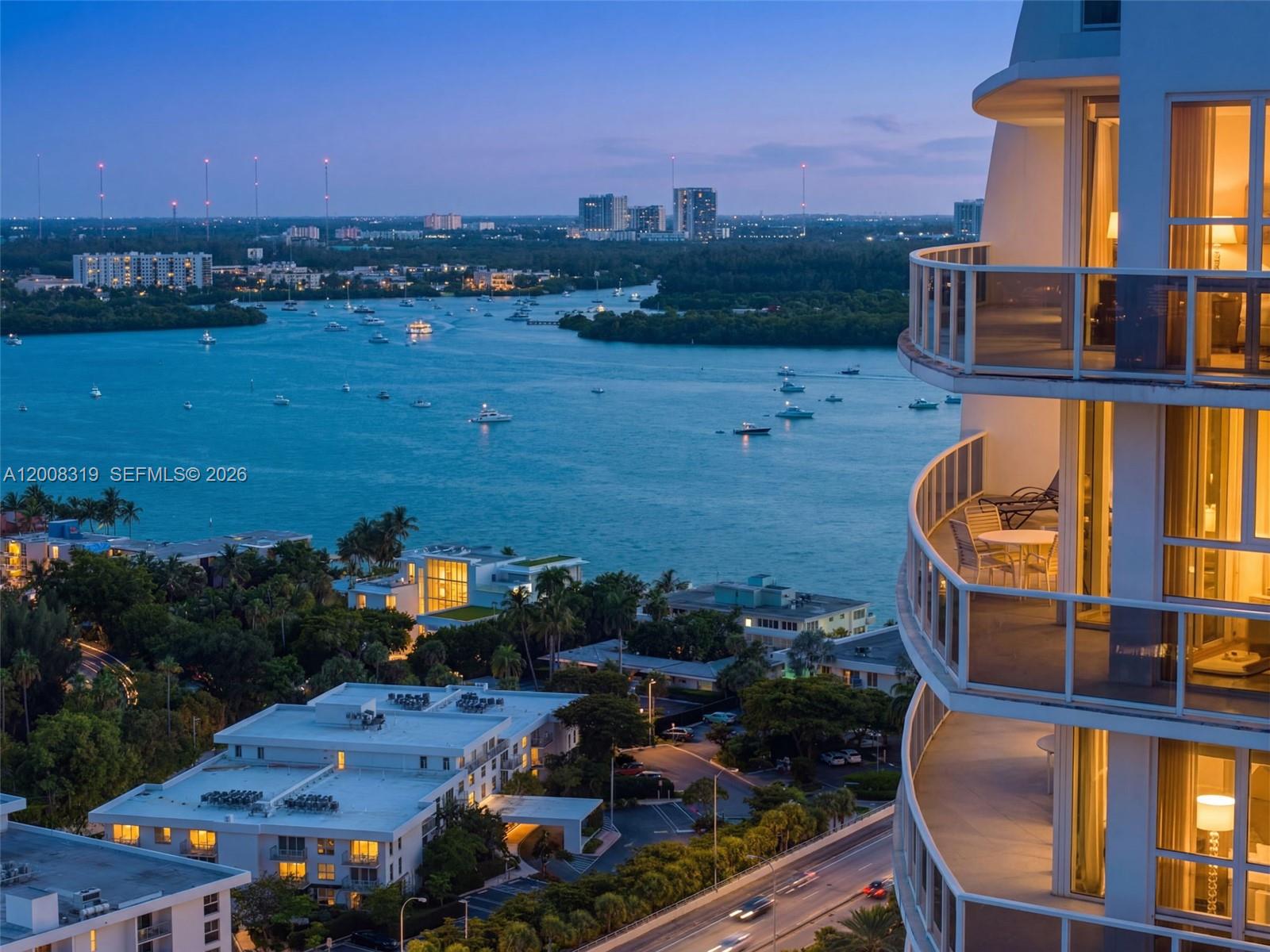 A high-angle view shows a curved balcony overlooking a bay with boats and city buildings — 10225 Collins Ave # 2004, Bal Harbour FL 33154, BAL HARBOUR, FL