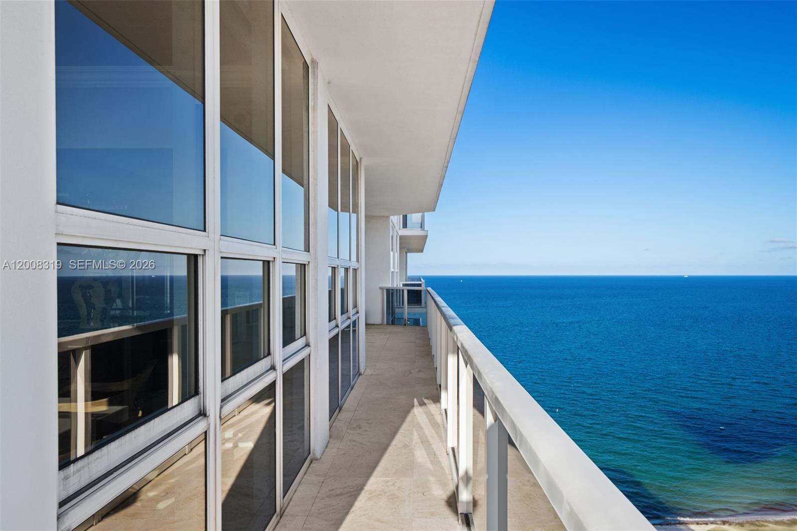A high-rise balcony features glass railings and floor-to-ceiling windows overlooking the ocean — 10225 Collins Ave # 2004, Bal Harbour FL 33154, BAL HARBOUR, FL