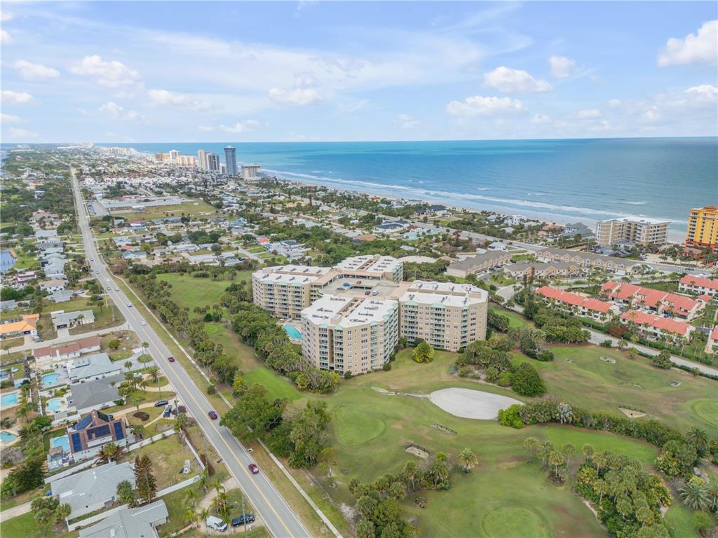 An aerial view shows a large apartment complex situated near a golf course and beach — 4 OCEANS WEST BOULEVARD UNIT 402A, DAYTONA BEACH, FL