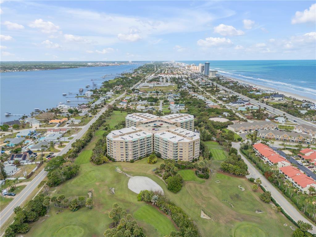 An aerial view shows a large condominium complex situated on a golf course near the coast — 4 OCEANS WEST BOULEVARD UNIT 402A, DAYTONA BEACH, FL