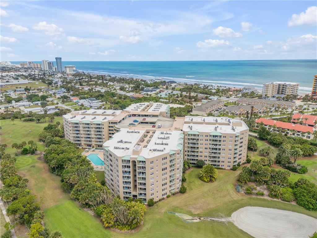 An aerial view shows a large multi-story apartment complex situated on a golf course near the ocean — 4 OCEANS WEST BOULEVARD UNIT 402A, DAYTONA BEACH, FL