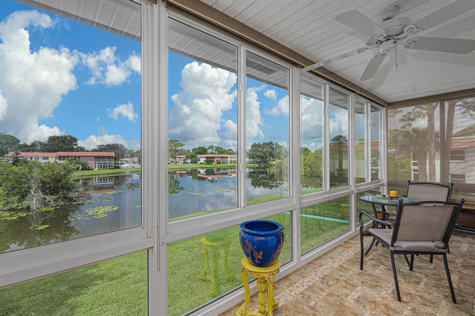 A sunroom with tile flooring, a ceiling fan, and large windows overlooking a pond — 1225 NW 21st Street # 708, Stuart FL 34994, STUART, FL