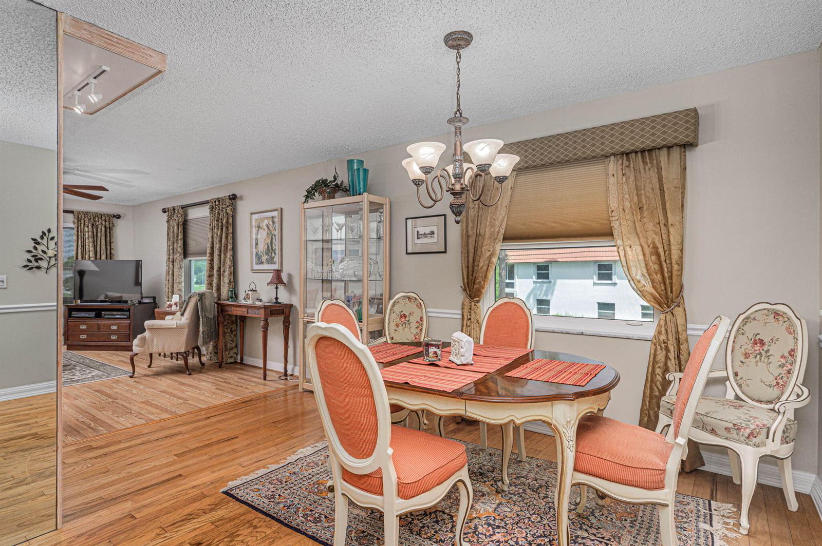 A dining room with a wooden table, floral chairs, a chandelier, and an adjacent living area — 1225 NW 21st Street # 708, Stuart FL 34994, STUART, FL