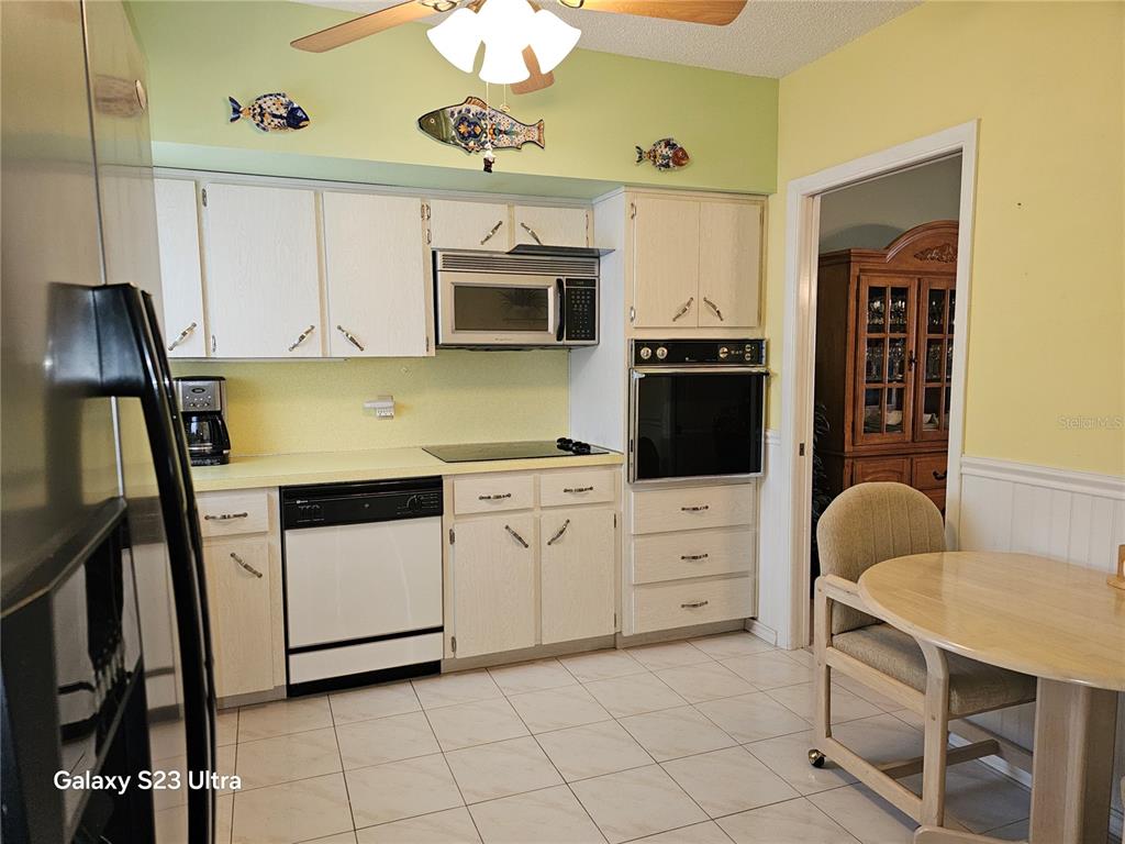 A kitchen with white cabinets, light countertops, a built-in oven, and decorative fish wall art — 2440 WORLD PARKWAY BOULEVARD UNIT 46, CLEARWATER, FL
