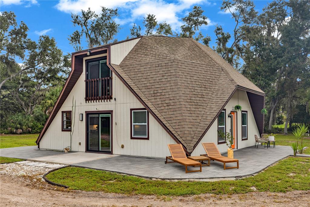 A geodesic dome house with a shingled roof, light siding, and a paved patio area — 1213 BUTCH CASSIDY TRAIL, WIMAUMA, FL