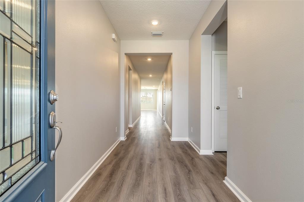 A view from an entryway looking down a long hallway with wood-look flooring — 89 SIGNET CIRCLE, FLAGLER BEACH, FL