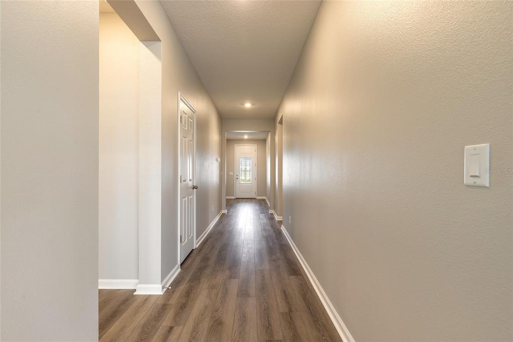A long hallway with wood-look flooring leads to a white front door — 89 SIGNET CIRCLE, FLAGLER BEACH, FL