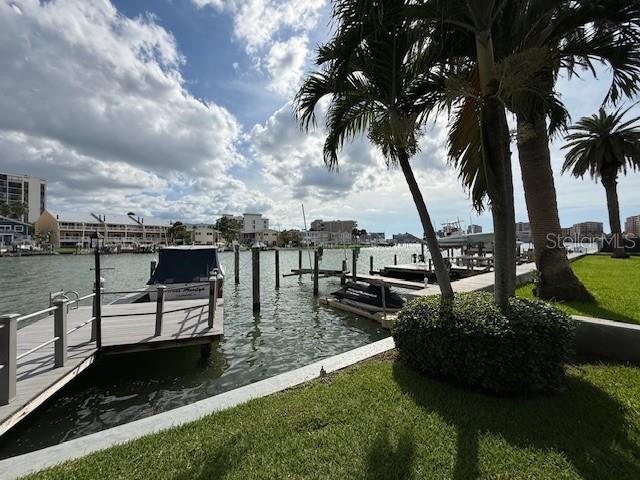 A stone picnic table sits on a grassy lawn overlooking a canal with docked boats — 430 LARBOARD WAY UNIT 3, CLEARWATER BEACH, FL