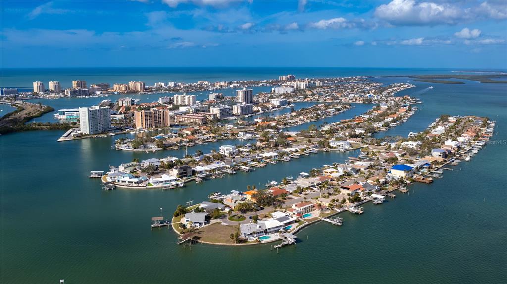 A wooden dock extends into a canal with boats and palm trees under a cloudy sky — 430 LARBOARD WAY UNIT 3, CLEARWATER BEACH, FL