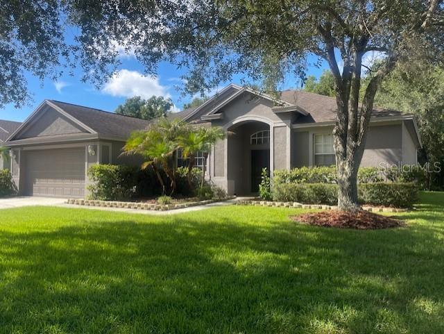 A single-story gray house with a two-car garage, arched entryway, and a large front lawn — 8343 TORRINGTON AVENUE, TAMPA, FL