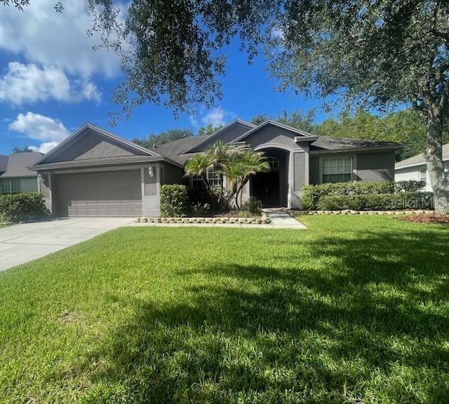 A single-story gray house with a two-car garage and a front lawn under trees — 8343 TORRINGTON AVENUE, TAMPA, FL