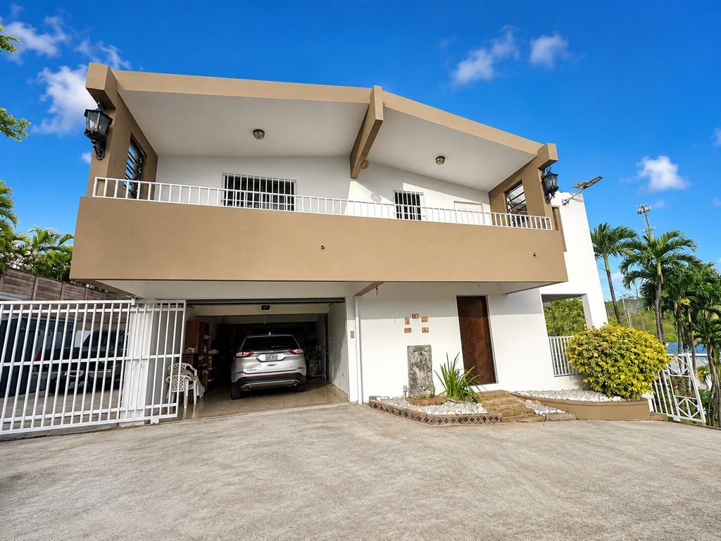 A two-story house with a tan upper level, white lower level, and an open garage — Calle B# 7 URB. MONTE BRISA, GURABO, PR