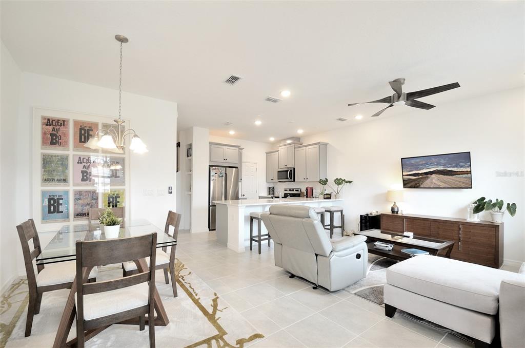 An open-concept living area features a dining space, a kitchen with gray cabinets, and a lounge — 2331 GARDEN BELLE DRIVE, CLERMONT, FL