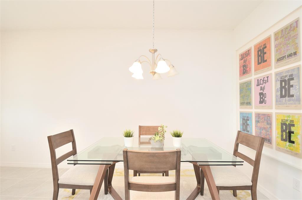 A dining room features a glass-topped table, wooden chairs, a chandelier, and wall art — 2331 GARDEN BELLE DRIVE, CLERMONT, FL