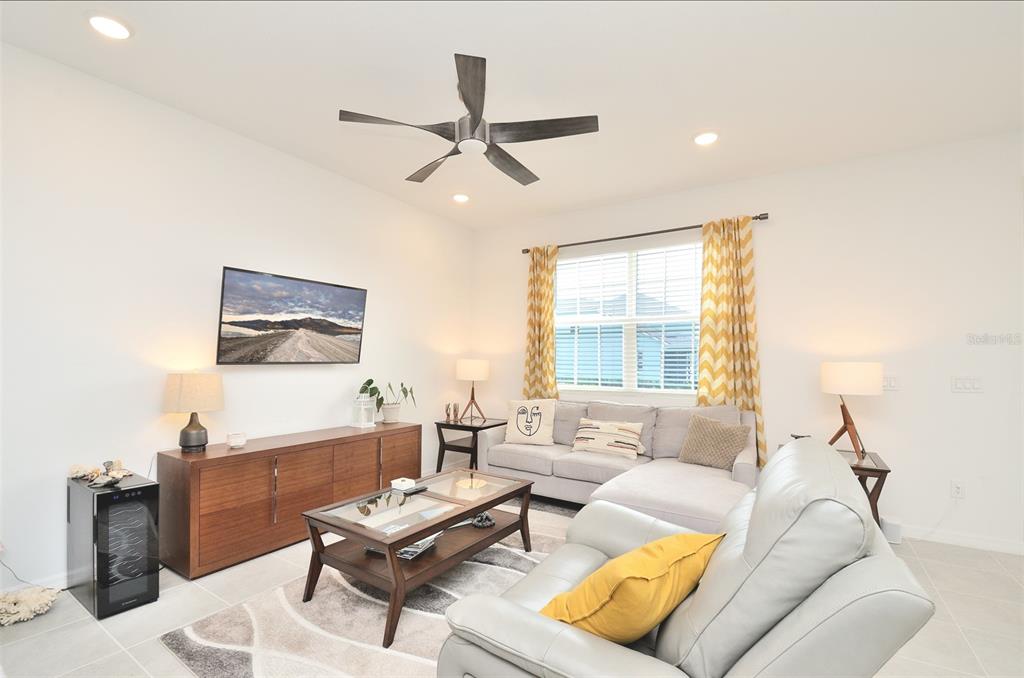 A living room features a grey sectional sofa, a wooden media console, and a ceiling fan — 2331 GARDEN BELLE DRIVE, CLERMONT, FL