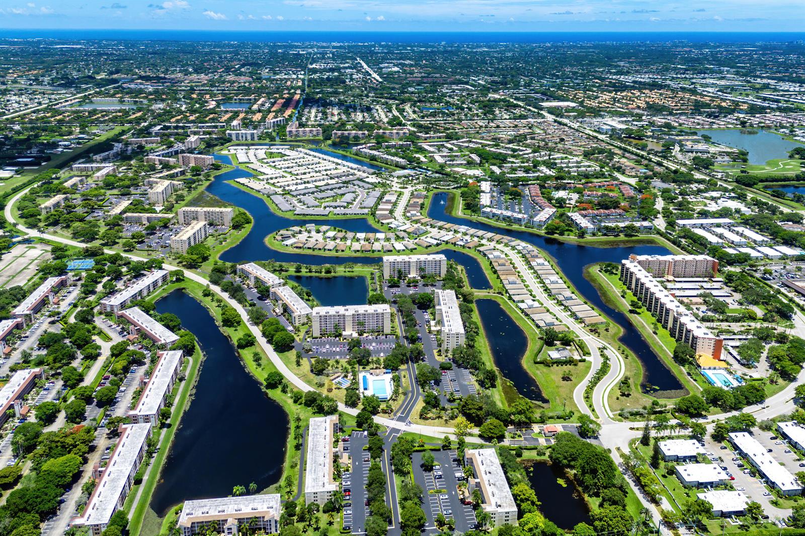 Aerial view of a residential apartment complex surrounded by winding lakes and green spaces — 7290 Kinghurst Drive # 607, Delray Beach FL 33446, DELRAY BEACH, FL