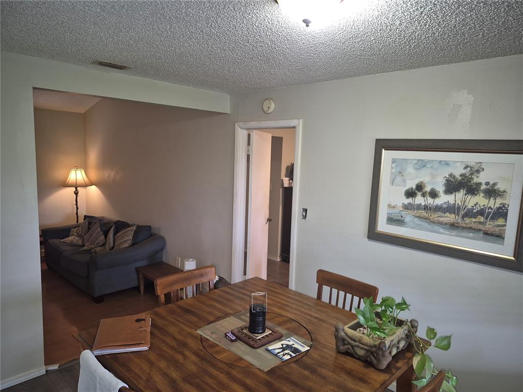 A dining area with a wooden table leads into a living room with a sofa — 13710 WHITBY ROAD, HUDSON, FL