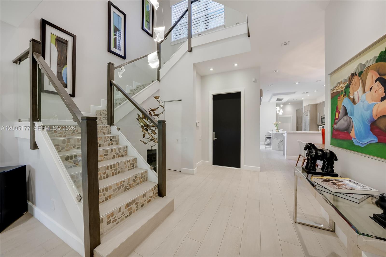 An entryway features a stone-tiled staircase, a black front door, and a large colorful painting — 1366 W Harbor Vw W, Hollywood FL 33019, HOLLYWOOD, FL