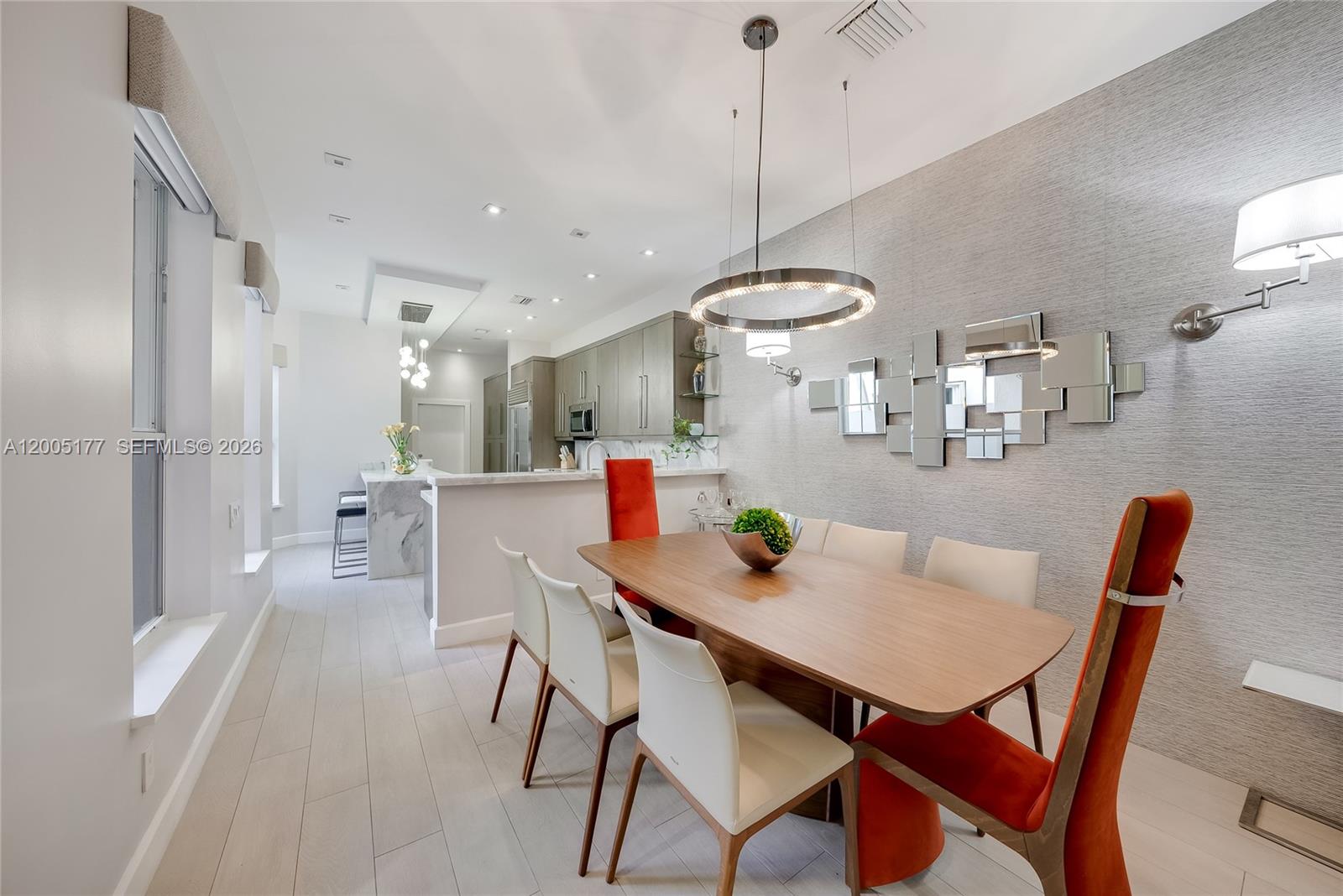 A dining area features a wooden table with white and orange chairs near a kitchen — 1366 W Harbor Vw W, Hollywood FL 33019, HOLLYWOOD, FL
