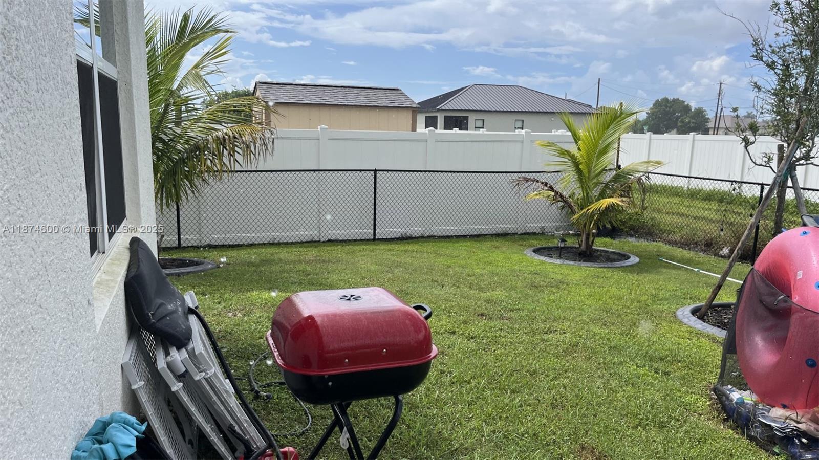 A backyard features a red charcoal grill, a chain-link fence, and two palm trees — 2829 NW 7 TERRACE, Cape Coral FL 33993, CAPE CORAL, FL