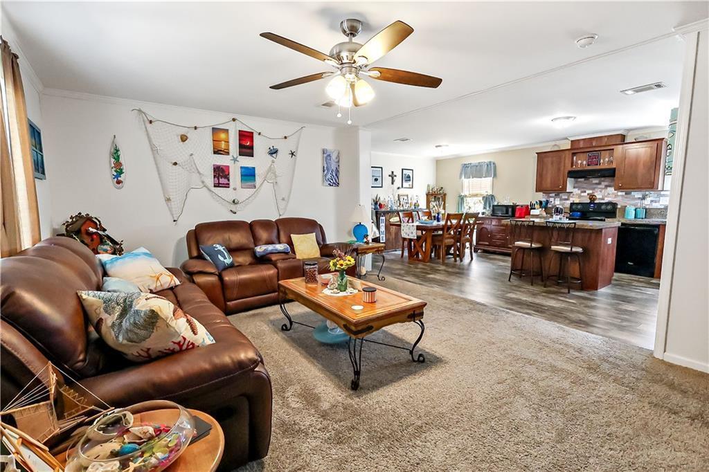 A living room with brown leather sofas and a coffee table opens to a kitchen — 324 Valencia Street, Sebastian FL 32958, SEBASTIAN, FL