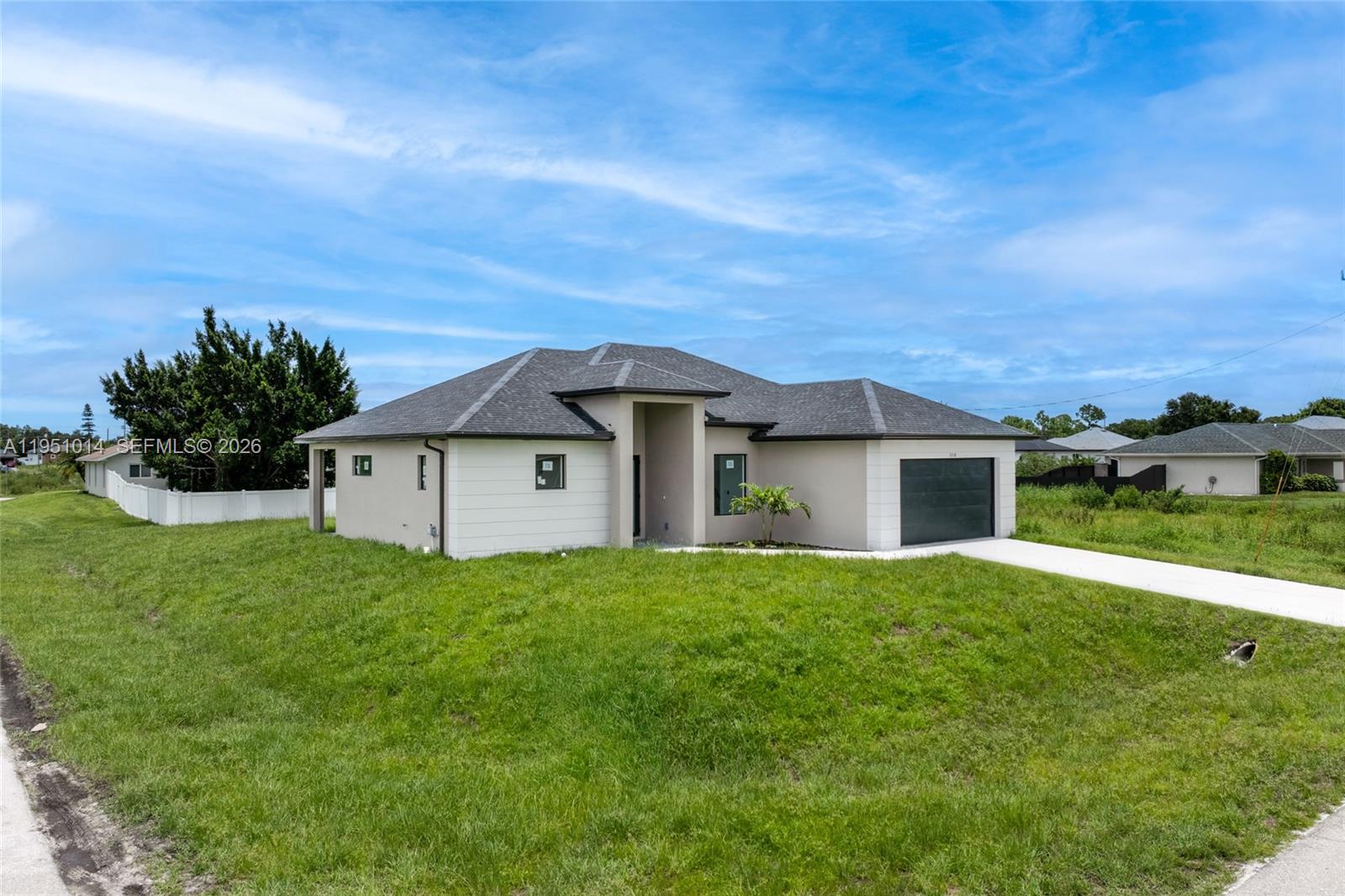 A single-story house with a dark roof, light siding, and an attached garage — 3318 30th St SW, Lehigh Acres FL 33976, LEHIGH ACRES, FL
