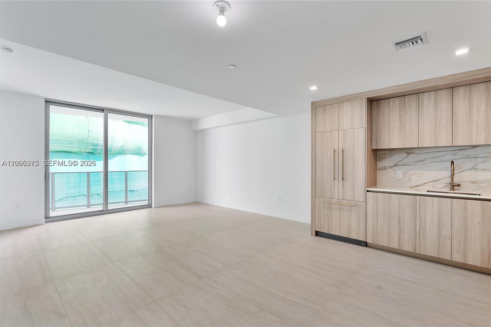 A modern room features light wood cabinetry, a marble backsplash, and a sliding glass door — 77 SE 5th St # 4106, Miami FL 33131, MIAMI, FL