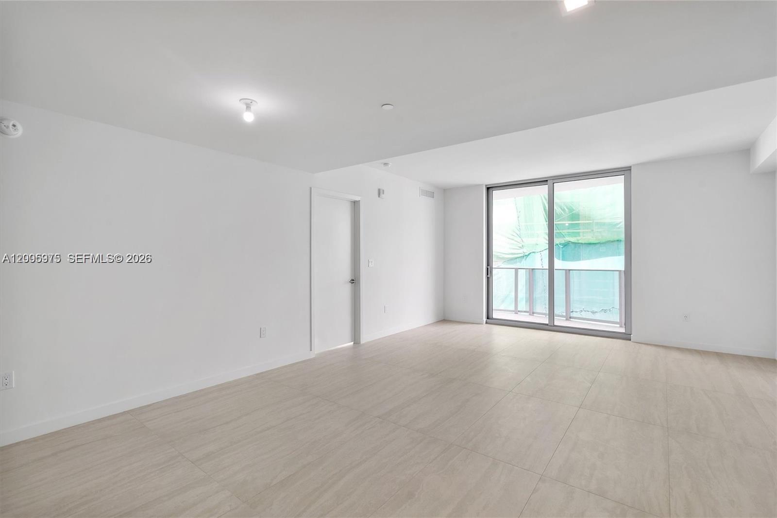 An empty room features white walls, light-colored tile flooring, and a sliding glass door — 77 SE 5th St # 4106, Miami FL 33131, MIAMI, FL