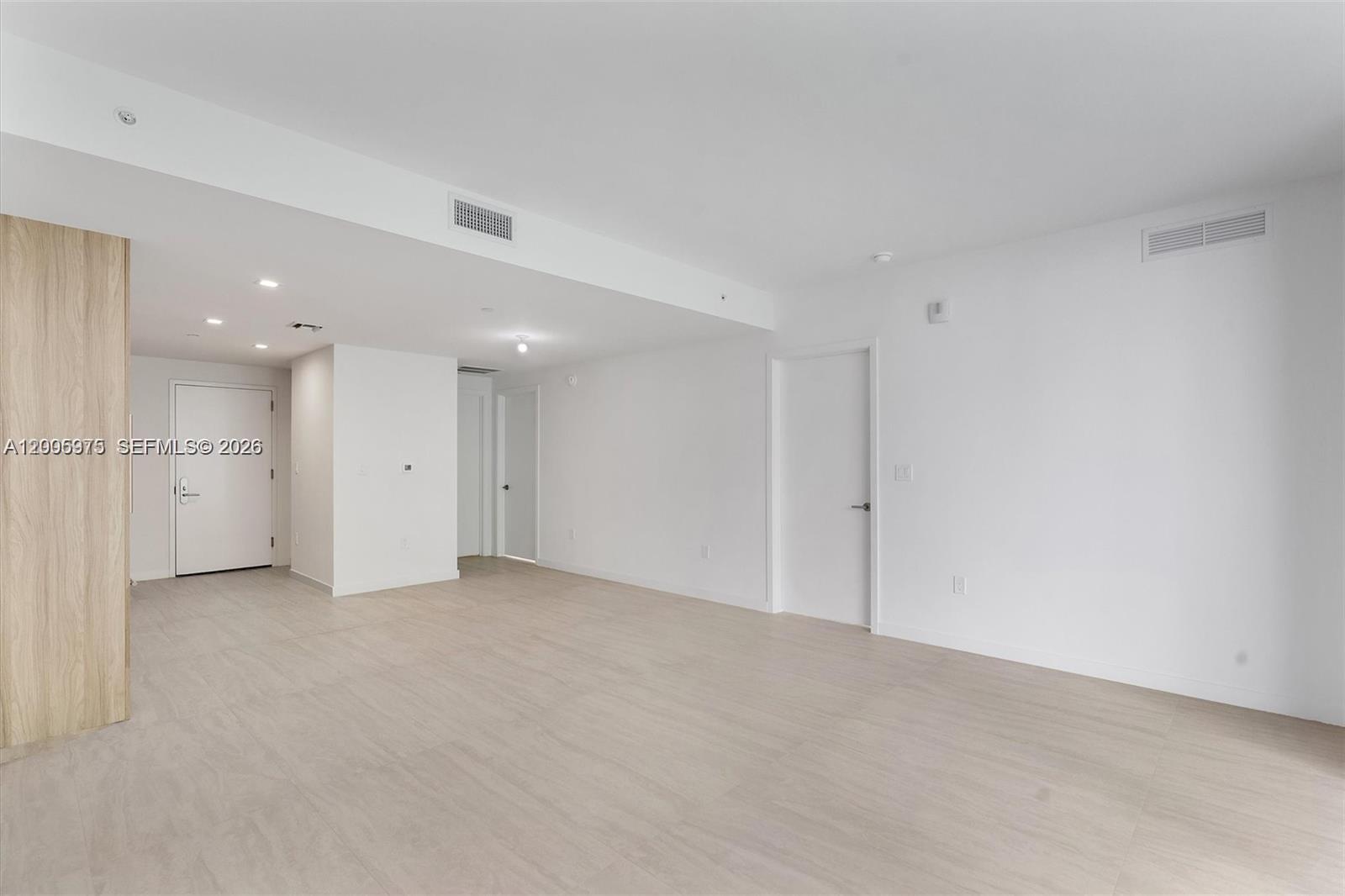 An empty room features white walls, light wood-look flooring, and several interior doors — 77 SE 5th St # 4106, Miami FL 33131, MIAMI, FL