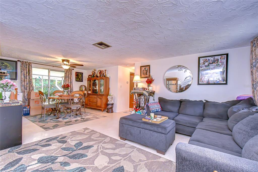 A living room with a gray sectional sofa, a dining area, and a patterned area rug — 2128 SHANNON DRIVE, HOLIDAY, FL
